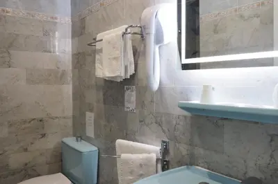 a blue tiled bathroom with a tub and a sink at Hotel Busby in Nice