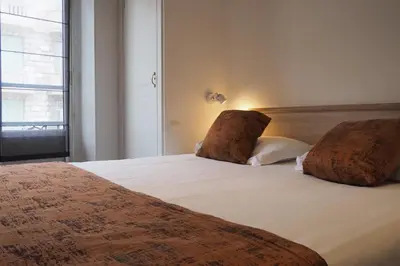 a hotel room with two beds and two lamps at Hotel Busby in Nice