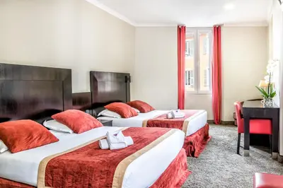 a hotel room with three beds and a desk at Hotel De Suède in Nice
