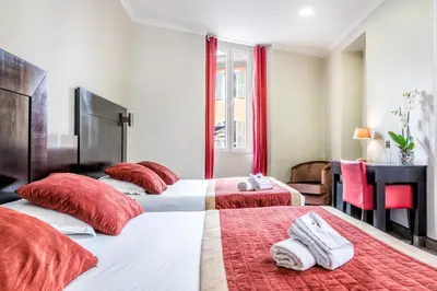 two beds in a hotel room with red pillows at Hotel De Suède in Nice