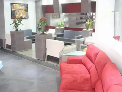 a waiting room with a red couch and chairs at Hotel De Suède in Nice
