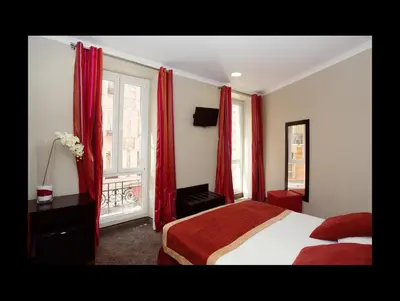 a bedroom with red curtains and a bed and a window at Hotel De Suède in Nice