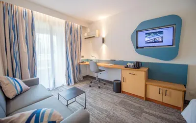 a hotel room with a couch and a desk and a tv at Promotel in Carros