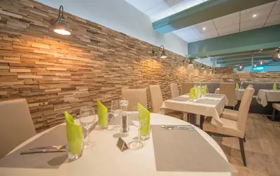 a restaurant with white tables and chairs and a brick wall at Promotel in Carros