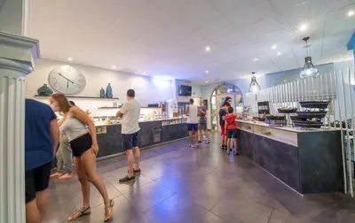a group of people standing at a counter in a restaurant at Promotel in Carros