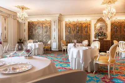 a dining room with white tables and chairs and chandeliers at Hotel Le Negresco in Nice