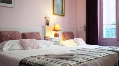 a bedroom with two beds and a lamp and a window at Hotel des Dames in Nice