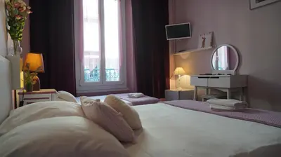 a bedroom with a large white bed with a mirror at Hotel des Dames in Nice