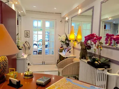 a living room with a table and a mirror at Hotel des Dames in Nice