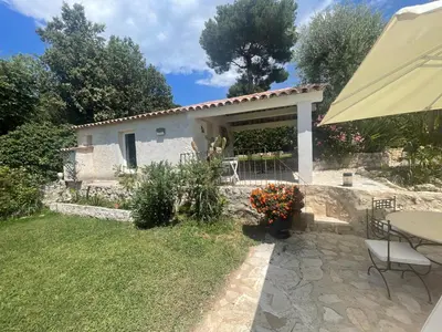 a white house with a table and chairs in a yard at La Bergerie B&B in Vence