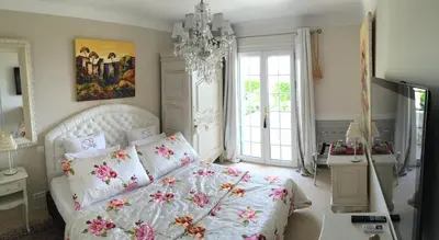 a bedroom with a white bed and a chandelier at La Bergerie B&B in Vence