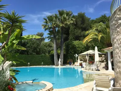 a swimming pool with chairs and palm trees at La Bergerie B&B in Vence