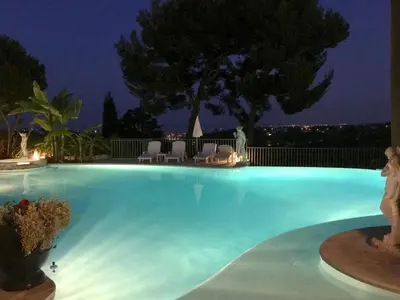 a swimming pool at night with chairs and trees at La Bergerie B&B in Vence