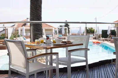 a table and chairs on a balcony with a pool at Boutique Hotel & Spa la Villa Cap Ferrat in Saint-Jean-Cap-Ferrat