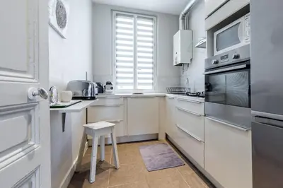 a kitchen with white appliances and a stool in it at Beautiful apartment by the sea front in Nice