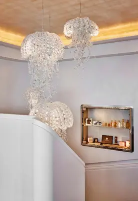 two crystal chandeliers hanging from a wall with a mirror at La Réserve de Beaulieu in Beaulieu-sur-Mer