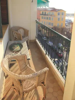 a balcony with wicker chairs and a table on a balcony at Le Lympia in Nice