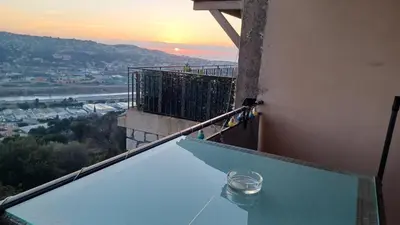 a balcony with a table with a view of a sunset at La Tuiliere in Saint-Laurent-du-Var