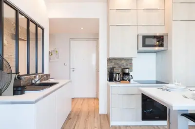 a kitchen with white cabinets and a counter top at Sea View - Promenade des Anglais 1 Bdr in Nice