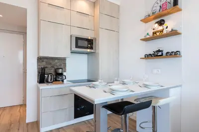 a kitchen with a white island with a microwave at Sea View - Promenade des Anglais 1 Bdr in Nice