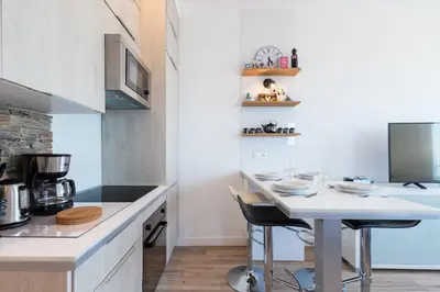 a kitchen with a white counter and a table with chairs at Sea View - Promenade des Anglais 1 Bdr in Nice