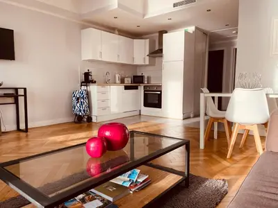 a living room with a glass coffee table and a kitchen at Appartement 2 chambres avec Terrasse Vue sur la Mer in Nice