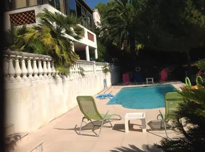 a swimming pool with two lawn chairs next to a house at La Nectarine in Nice