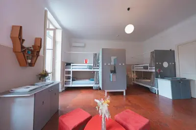 a large living room with red chairs and a kitchen at La Maïoun Guesthouse in Nice