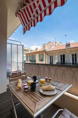 a table with food on a balcony with an umbrella at Appartement Musiciens in Nice