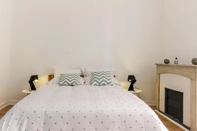 a bedroom with a white bed with a fireplace at MY CASA - VEILLON - 2 bedrooms - City Center in Nice
