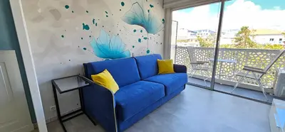 a blue couch in a living room with a mural at Affitto-Nizza in Nice