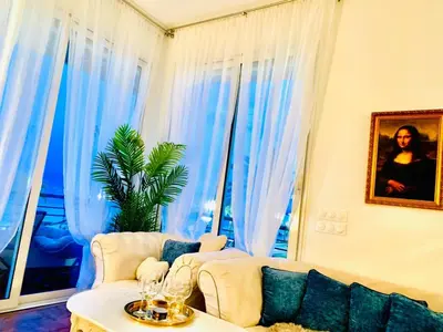 a living room with blue curtains and a couch at Endless Stunning Mediterranean Sea Views Promenade Des Anglais in Nice