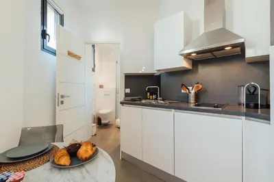 a kitchen with white cabinets and a plate of food on a table at Le Foch in Nice