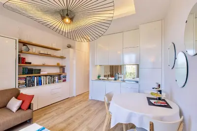 a kitchen and living room with a table and a couch at GRAND HÔTEL Golden Square 3 min to Beach Green Corridor View AC in Nice