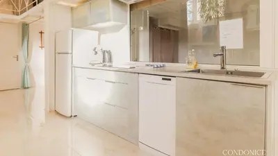 a white kitchen with a sink and a refrigerator at CondoNice in Nice