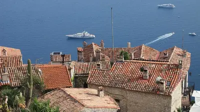 a cruise ship in the water with houses and roofs at Eze Monaco middle of old town of Eze Vieux Village Romantic Hideaway with spectacular sea view in Èze