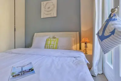 a bedroom with a white bed with a book on it at MY CASA - FRANCE 82 D - 2 rooms - Terrace - 1 min to the Sea in Nice