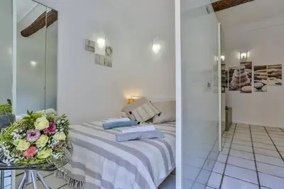 a white bedroom with a bed and flowers on a table at MY CASA - MARI 117 - City Center in Nice