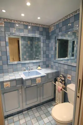 a blue tiled bathroom with a toilet and a sink at La Reale in Villefranche-sur-Mer