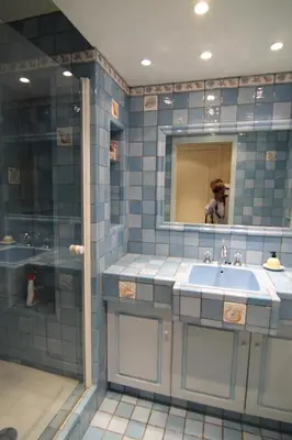 a woman taking a picture of a blue tiled bathroom at La Reale in Villefranche-sur-Mer