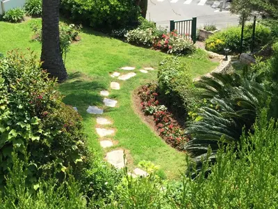a garden with rocks and flowers in a yard at La Reale in Villefranche-sur-Mer