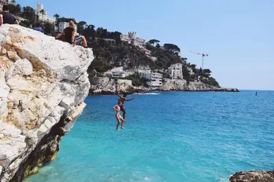 a person jumping off a cliff into the water at Apartment Lisa Acropolis Garibaldi in Nice