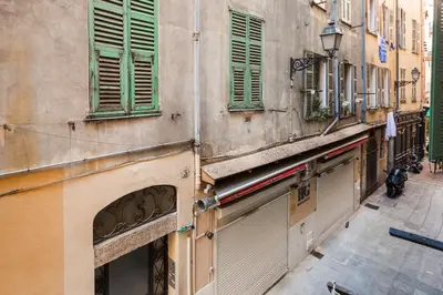 a building with green shuttered windows on a street at Moulin -Old Town in Nice