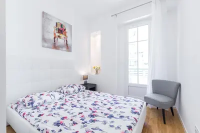 a white bedroom with a bed and a chair at Nice Beach - Promenade Des Anglais in Nice