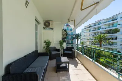 a balcony with a couch and chairs and a building at Nice Beach - Promenade Des Anglais in Nice
