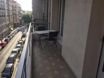 a balcony with a table and cars on a city street at Le Palais Martine in Nice
