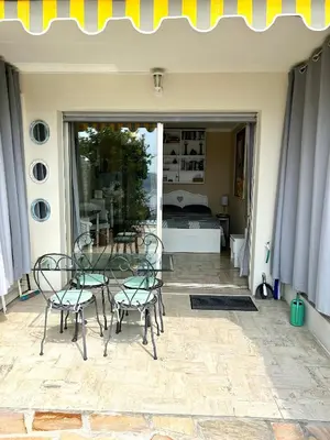 a patio with a glass table and chairs and a bedroom at Studio Leopolda in Villefranche-sur-Mer