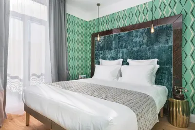 a bedroom with a large bed with a green wall at The Jay Hotel by HappyCulture in Nice