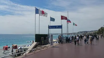 a group of people walking on a beach with flags at Palais Rialto in Nice