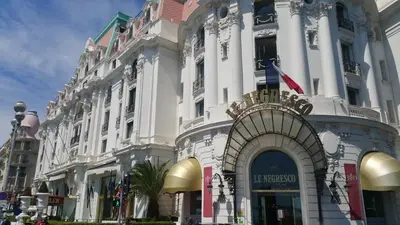 a large white building with an archway on a street at Palais Rialto in Nice